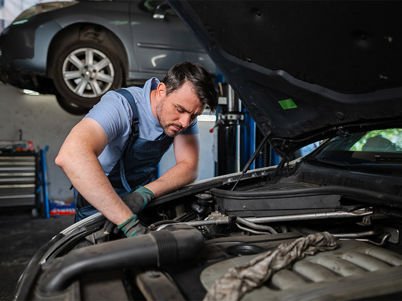 Mechaniker arbeitet am Motor eines Pkw in einer Autowerkstatt in Sinzig und führt Reparaturarbeiten im Motorraum durch