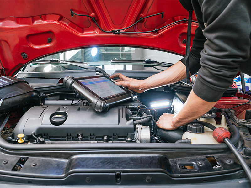 Mechaniker prüft mit einem Tablet den Motor eines Pkw in einer freien Werkstatt in Sinzig