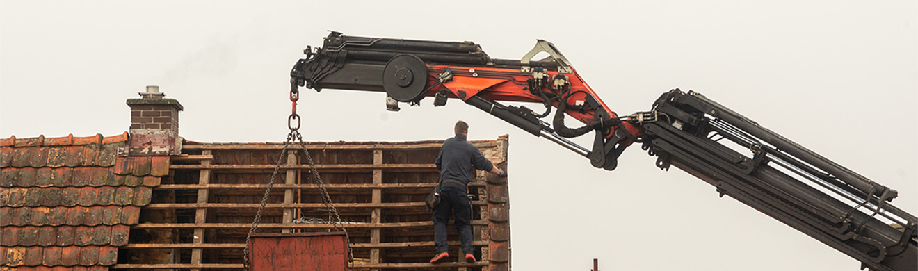 Handwerker reparieren altes Dach mit Dachziegeln und Werkzeugen – Dach sanieren im Brohltal.