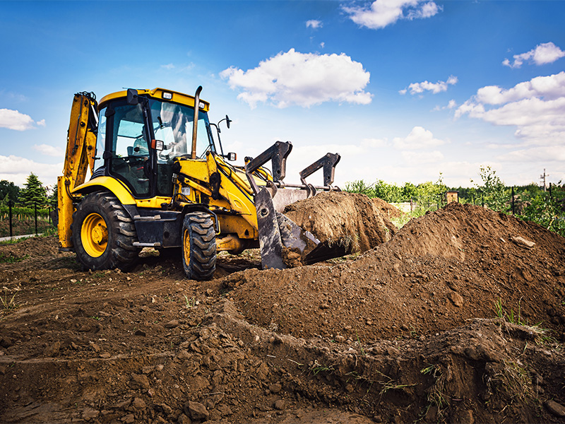 Bagger hebt Erde für eine Baugrube und das Fundament eines Hauses bei Erdarbeiten in Bad Neuenahr aus.