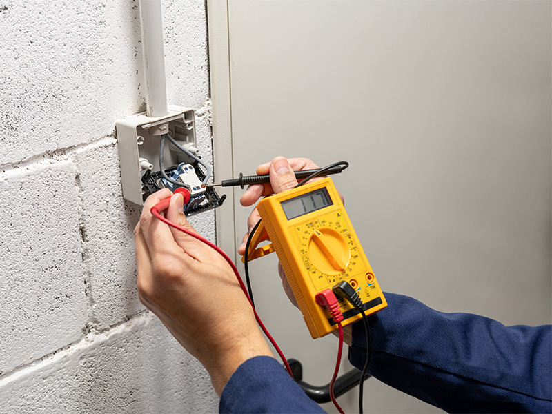 Elektriker misst die Spannung an einer Steckdose während der Elektroinstallation und prüft den fachgerechten elektrischen Anschluss.