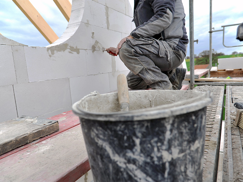 Maurer arbeitet auf Gerüst bei Maurerarbeiten im Kreis Ahrweiler, errichtet Mauerwerk an Baustelle im Hochbau.