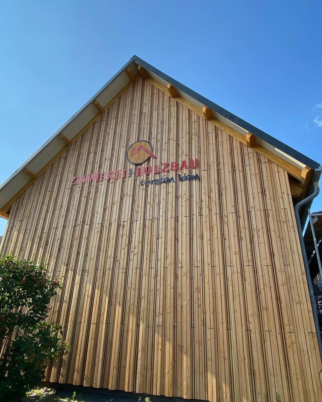 Helle Holzfassade einer modernen Seitenwand ohne Fenster, versehen mit dem Logo Holzbau Klein und klarer, geradliniger Struktur.