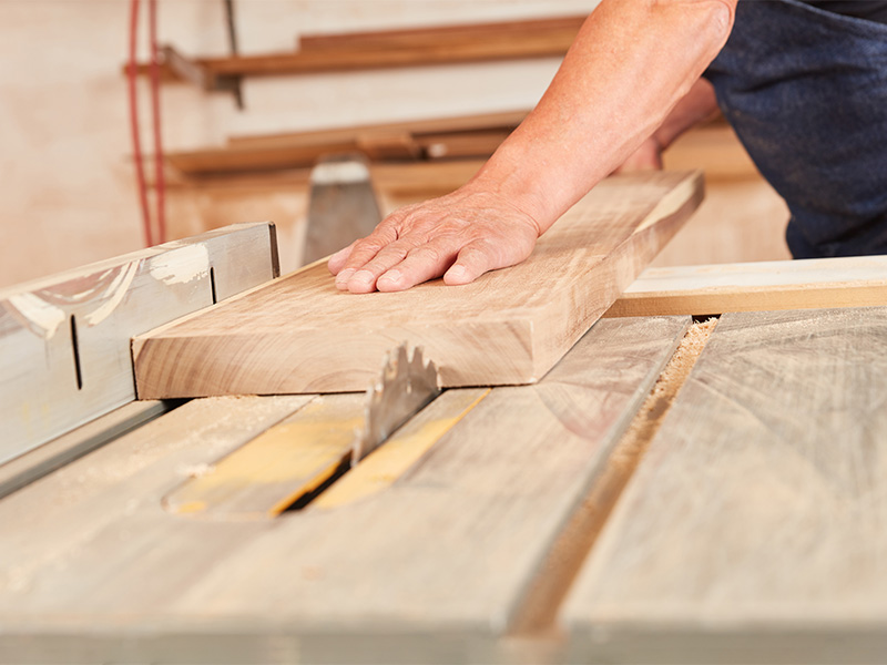 Handwerker sägt ein Holzbrett mit Kreissäge – Holzbau im Kreis Ahrweiler mit präziser Zimmerei Arbeit.
