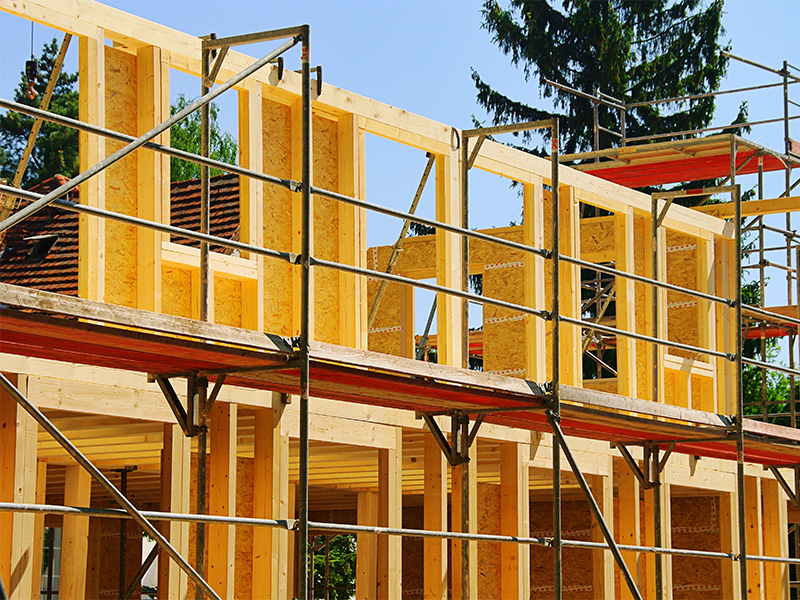 Holzrahmenbau im Kreis Ahrweiler: Facharbeiter montiert Holzrahmenstruktur auf Baustelle für energiesparendes Holzbauprojekt.