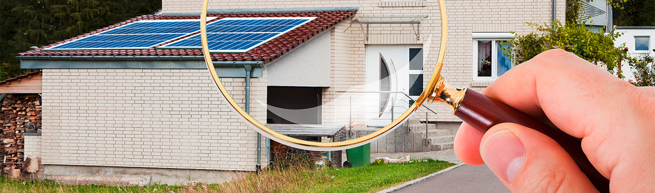 Person betrachtet ein Haus mit Lupe – Symbol für professionelle Immobilienbewertung im Kreis Ahrweiler.