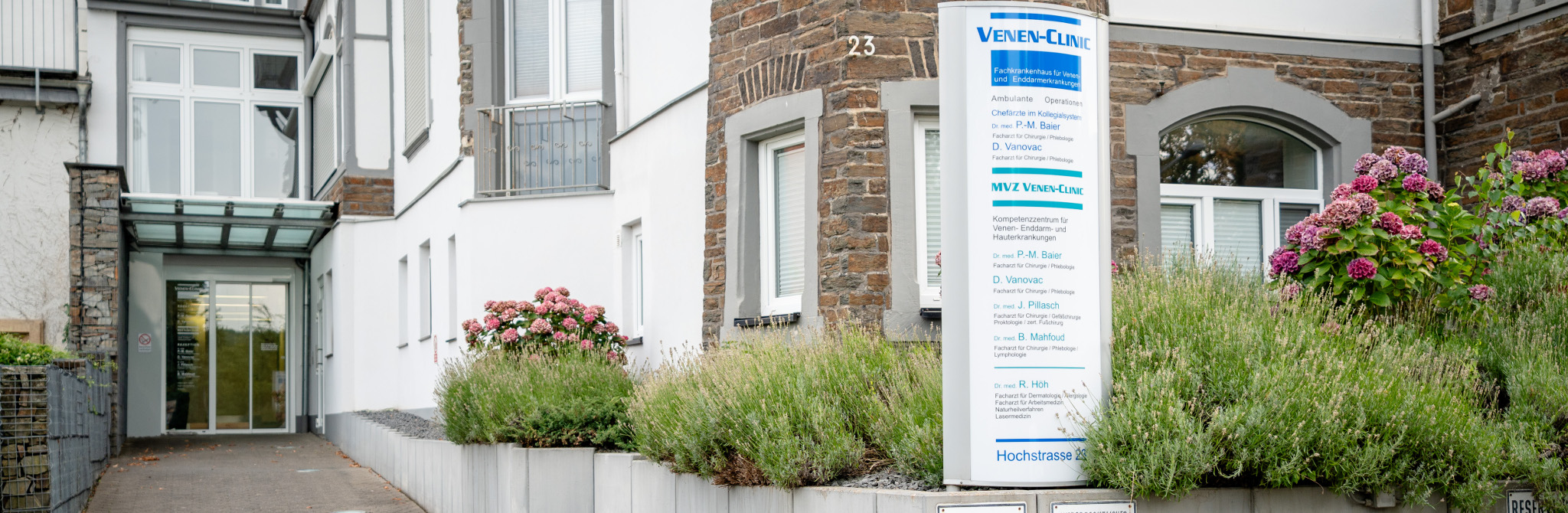 Außenansicht des Eingangs der VENEN-CLINIC in Bad Neuenahr-Ahrweiler mit großem Hinweisschild am Gebäude.