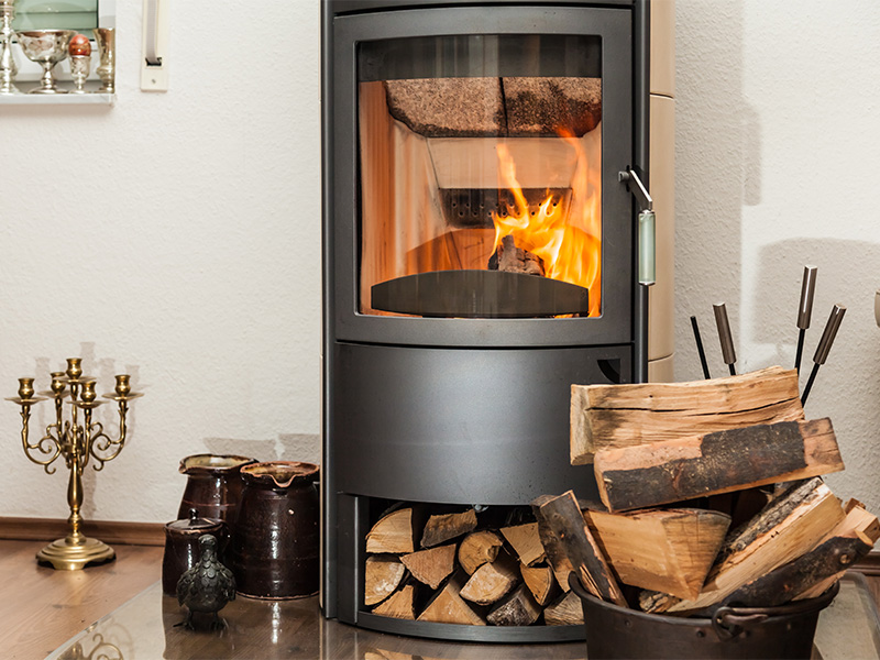 Wohnzimmer mit brennendem Kaminofen und gelagerten Holzscheiten als Inspiration zum Kaminofen kaufen im Kreis Ahrweiler