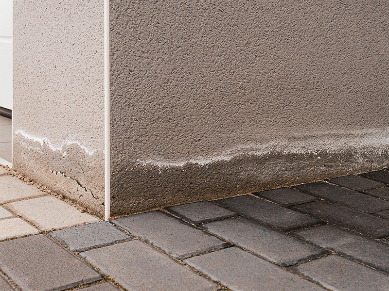 Mediatorin und Bauunternehmer begutachten Baumängel am Neubausockel, um einen Baustreit sachlich zu schlichten.