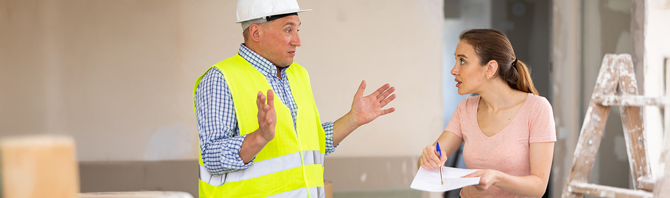 Verärgerte Frau hält Bauunterlagen in der Hand, im Streit mit Bauunternehmer während einer Renovierung.