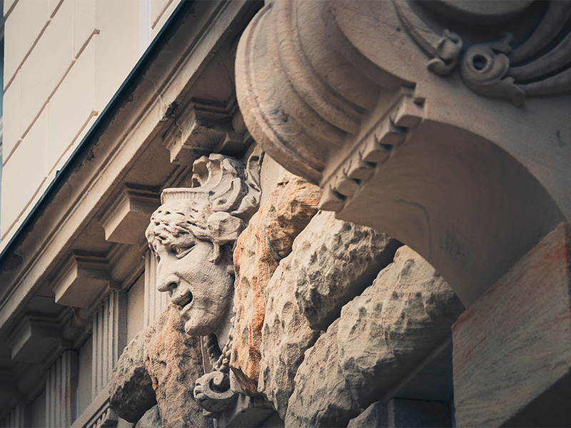 Verzierter Fassadenkopf aus Naturstein mit historischen Details als Beispiel für fachgerechte Natursteinsanierung.