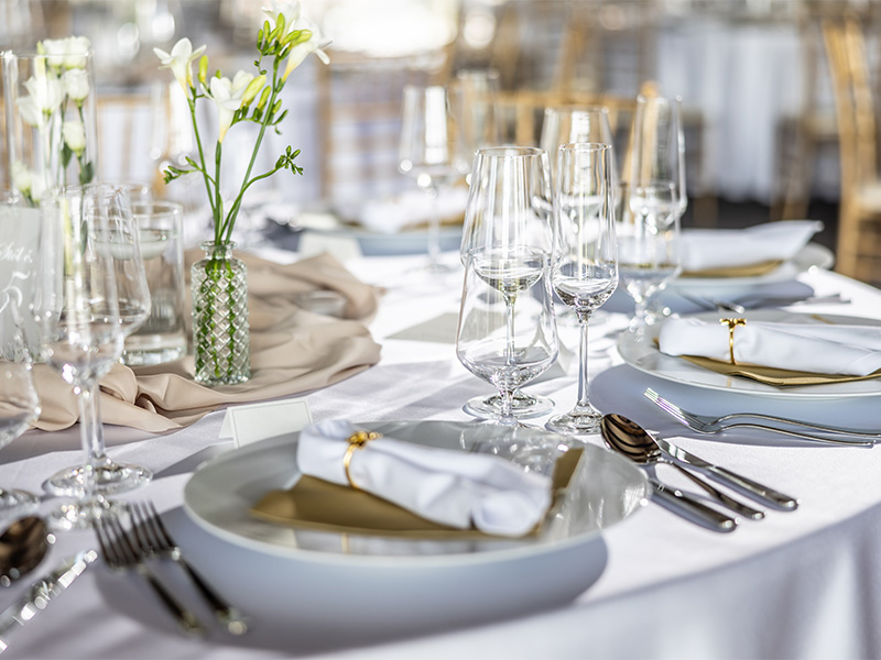 Festlich gedeckter Hochzeitstisch mit wei&szlig;er Tischdecke, Blumen, Kerzen, Gl&auml;sern und Besteck f&uuml;r eine stilvolle Feier.
