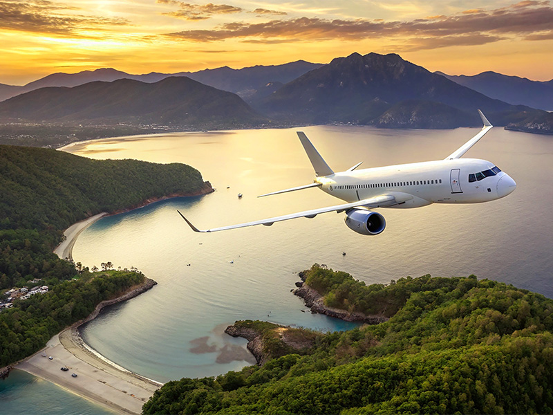 Passagierflugzeug fliegt bei Sonnenaufgang über Inseln und Meer – Inspiration für eine Flugreise buchen in Sinzig und entspanntes Reisen.
